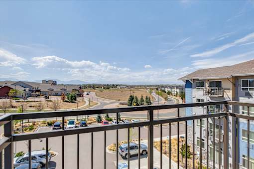 A balcony overlooks a parking lot and buildings.