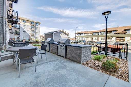 A patio with a table and chairs is surrounded by a black fence.