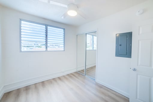 A room with a white door, a mirror, and a window with blinds.