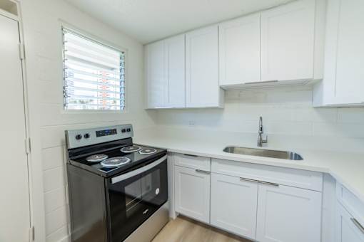 A kitchen with a stove, sink, and cabinets.