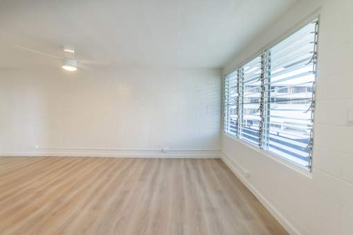 A room with wooden flooring and a window with blinds.