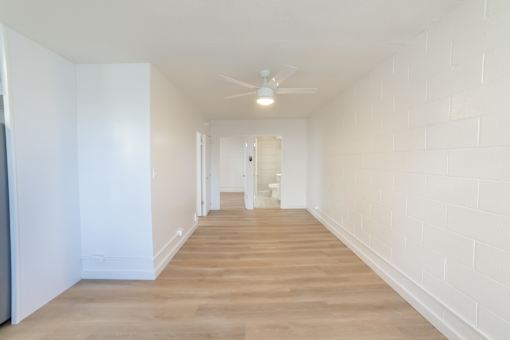 A long, empty hallway with wooden floors and white walls.