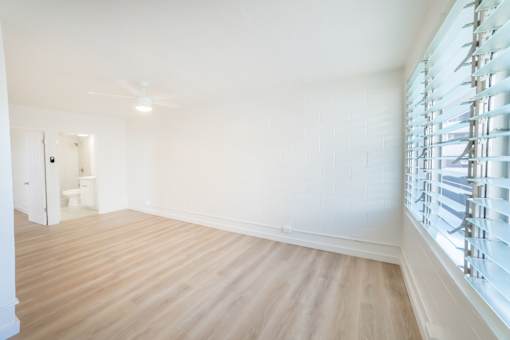 A room with wooden flooring and a window with blinds.