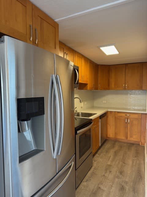 A kitchen with a stainless steel refrigerator and wooden cabinets.