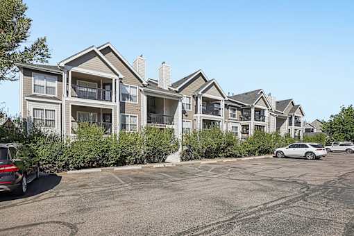 A row of houses with cars parked in front.