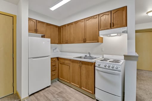 an empty kitchen with white appliances and wooden cabinets