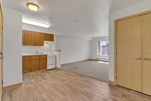 an empty living room and kitchen with wood flooring and a window