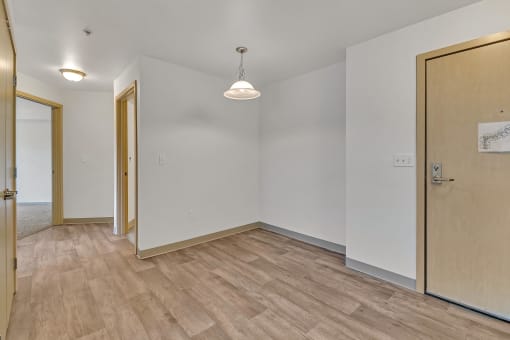 a living room with wood flooring and a door to a bedroom
