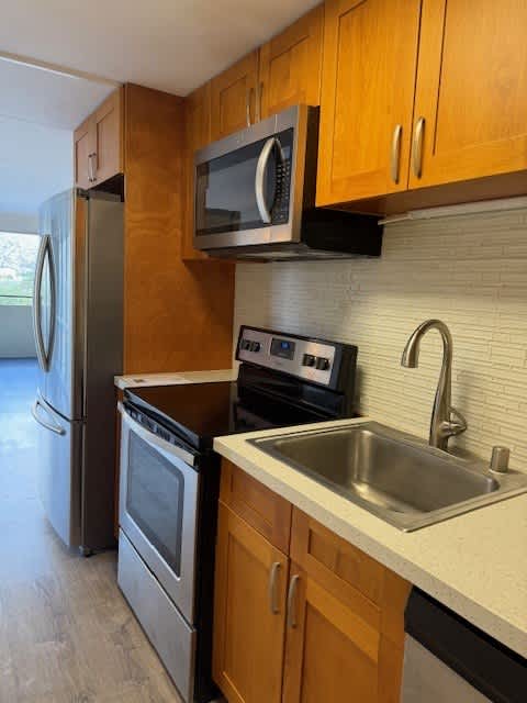 A kitchen with a refrigerator, oven, and microwave.