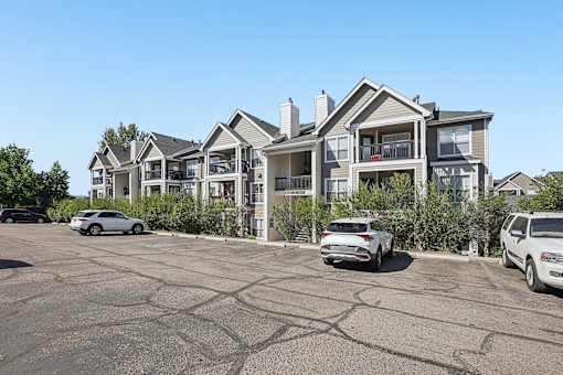 A parking lot with cars and apartment buildings in the background.
