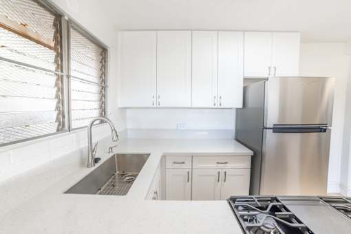 A kitchen with white cabinets and a stainless steel refrigerator.