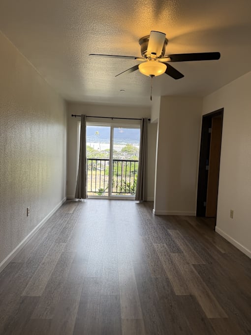 A room with a ceiling fan and sliding glass doors.