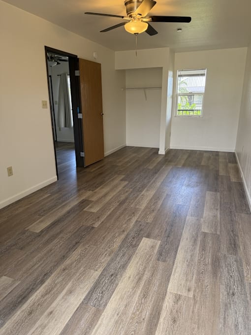 A room with a ceiling fan and wood flooring.