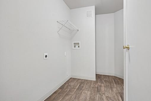 A white room with a door and a light switch on the wall.