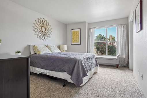 A bedroom with a bed, carpet, and a window.