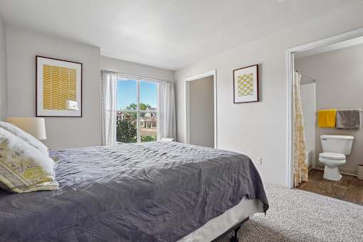 A bedroom with a bed, a toilet, and two pictures on the wall.