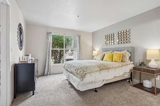 A bedroom with a bed, nightstand, and window.