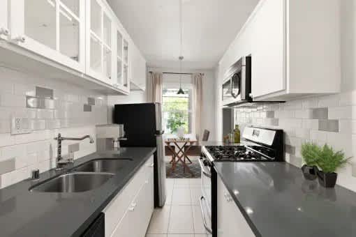 A modern kitchen with black countertops and white cabinets.