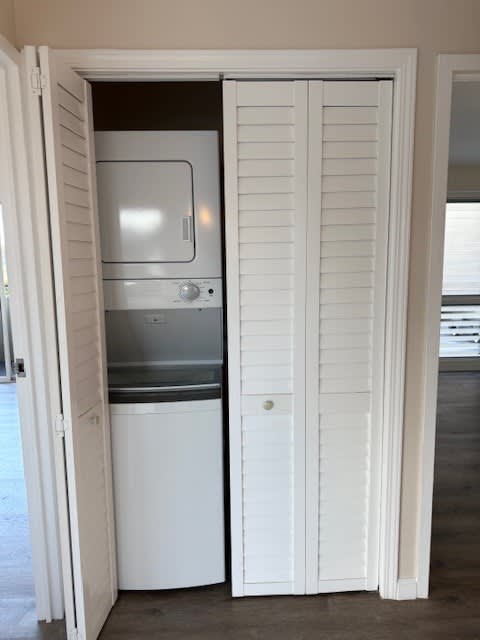 A white door is open to reveal a small kitchen with a sink and stove.