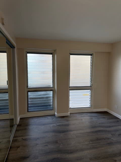 A room with two windows and a wooden floor.