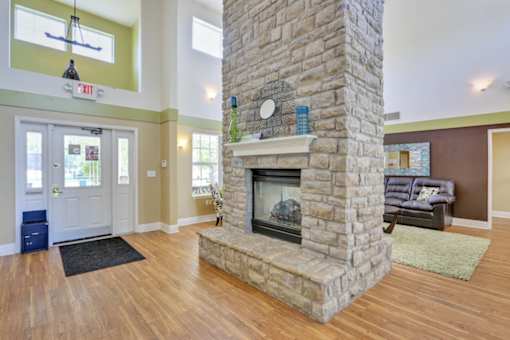 A stone fireplace in a room with a black rug in front of it.
