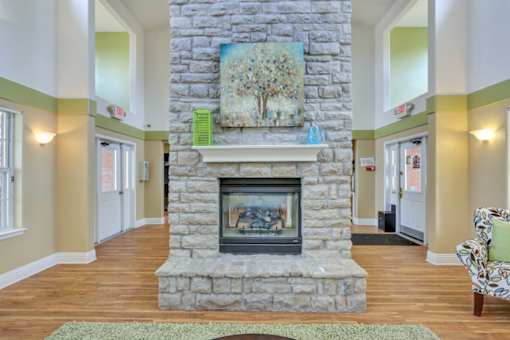 A stone fireplace with a painting above it in a room.