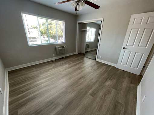 A room with a ceiling fan and a window with blinds.