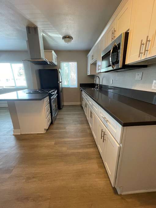 A kitchen with white cabinets and black countertops.