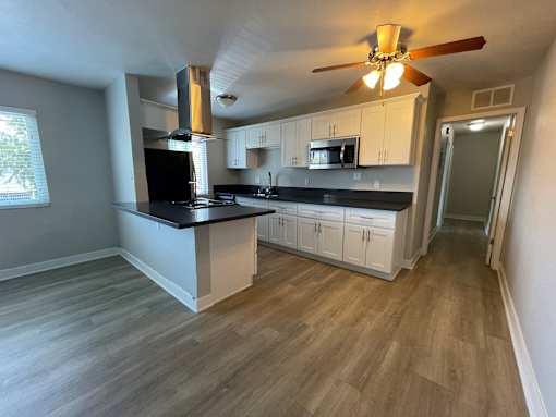 A kitchen with a black countertop and white cabinets.