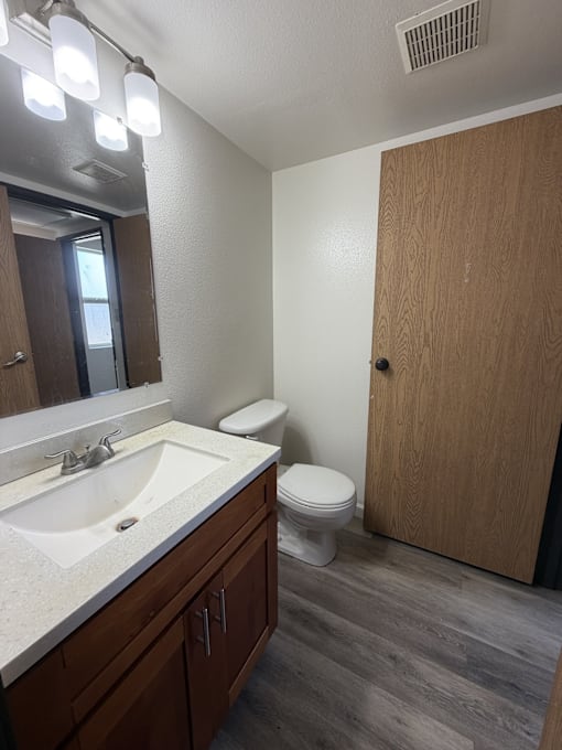 A bathroom with a sink, toilet, and mirror.