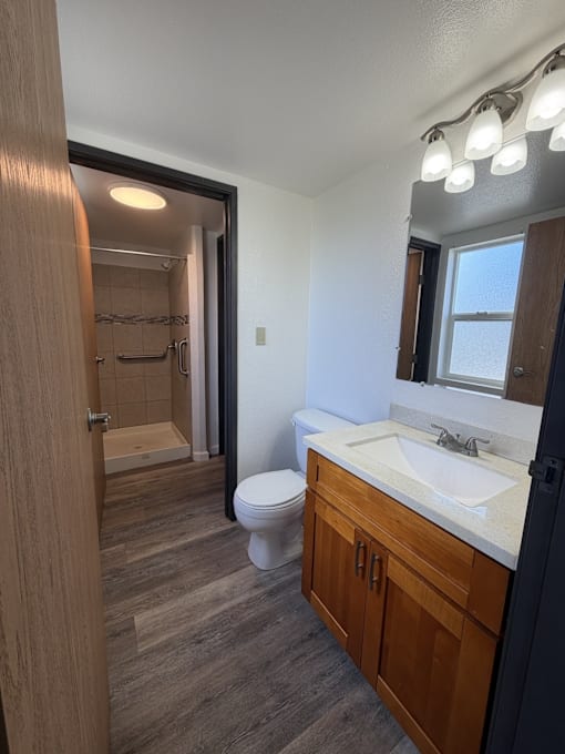 A bathroom with a toilet, sink, and mirror.