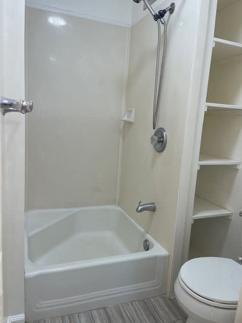 A white bathroom with a toilet and a walk in shower.