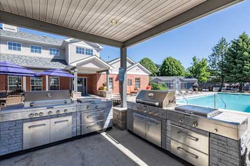 A large outdoor kitchen with a grill and a pool.