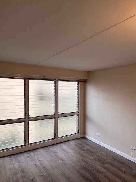 Napili Towers bedroom with a large window and wooden flooring.