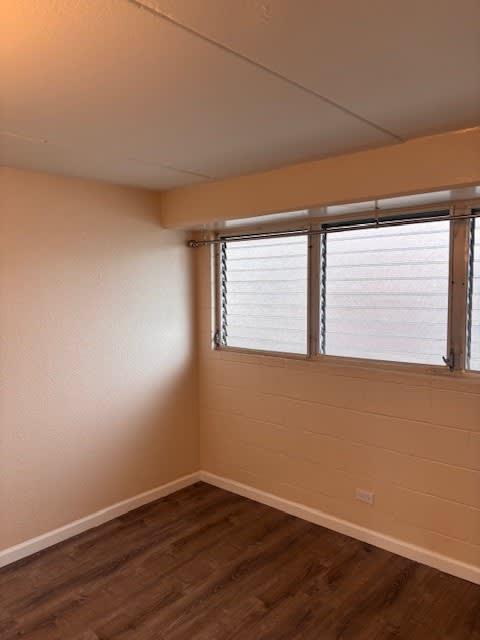 Napili Towers bedroom with wooden floors and a window.