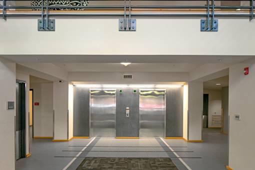 A hallway with two elevators and a fire extinguisher on the wall.