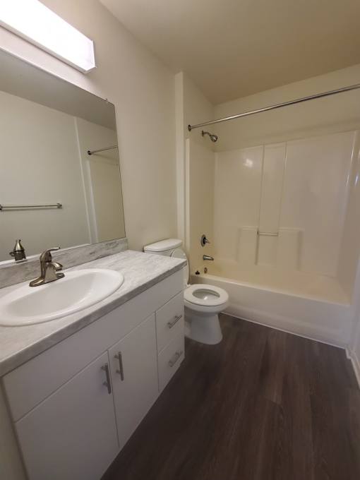 A white bathroom with a toilet, sink, and mirror.
