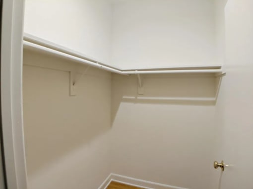 A white closet with a door and a shelf.
