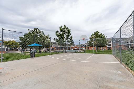 A basketball court is surrounded by a chain link fence.