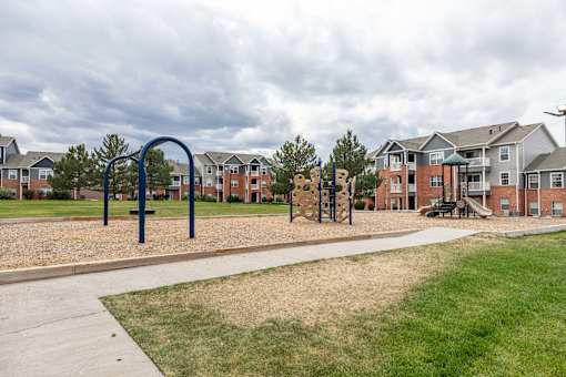 A playground with a blue swing set in front of apartment buildings.