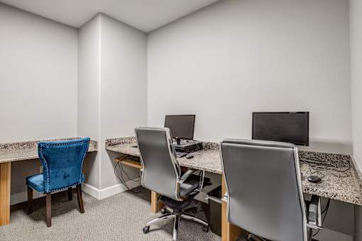 Three chairs are arranged around a desk with a computer monitor on it.