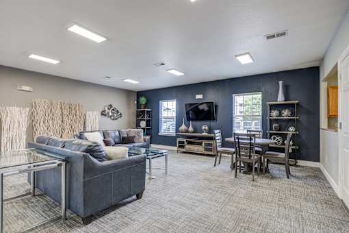 A living room with a grey couch and a glass coffee table.
