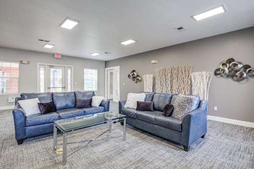 A living room with a blue couch and a glass coffee table.