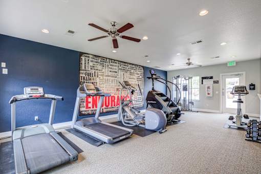 A gym with treadmills, elliptical machines, and a wall with a word cloud.