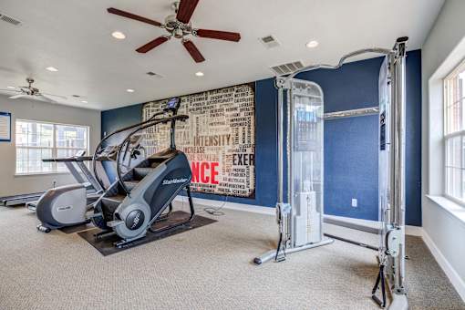 A home gym with a treadmill, elliptical trainer, and a wall with motivational words.