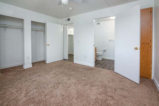A room with a carpeted floor and a ceiling fan.