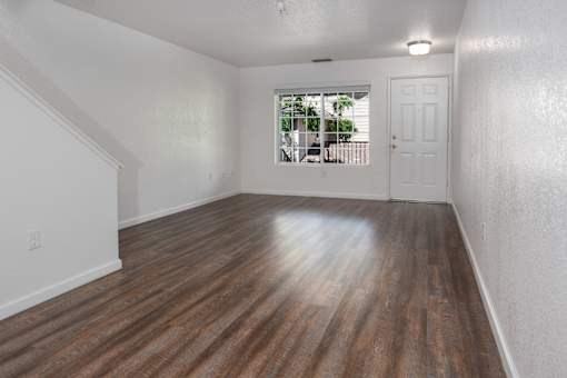 A room with wooden flooring and white walls.