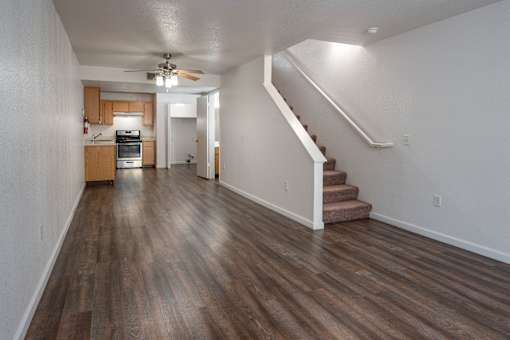 A long hallway with a staircase and a ceiling fan.