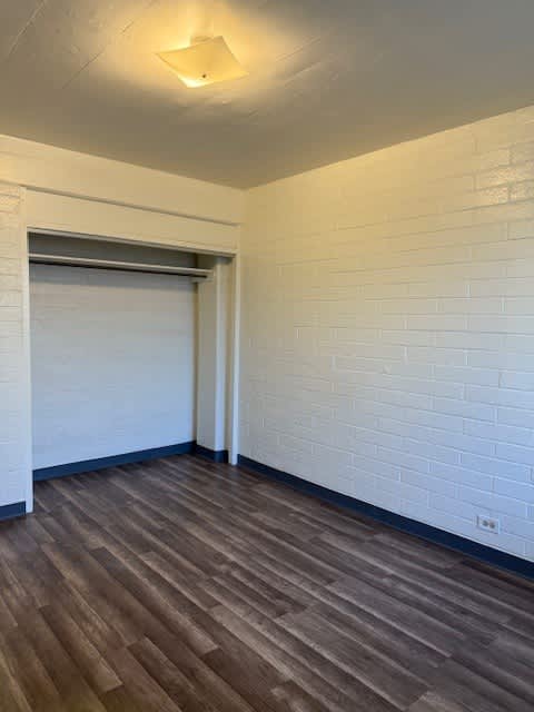 Pacific Oasis bedroom closet with a white brick wall and a brown wooden floor.