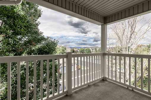 A balcony with a view of the sky and trees.